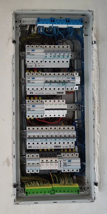 Rozdzielnica elektryczna z pięcioma rzędami aparatów i listwami przyłączeniowymi w domu w Sosnowcu.